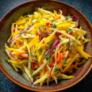 Colorful mango slaw with fresh vegetables and herbs in a bowl